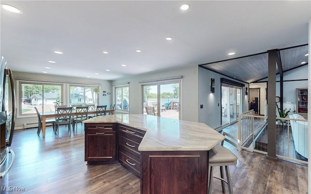 kitchen featuring dark wood-style flooring, recessed lighting, a kitchen breakfast bar, dark brown cabinetry, and light stone counters