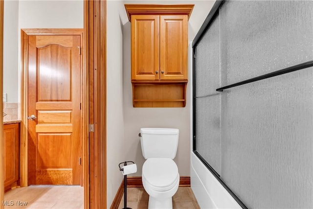 full bath with tile patterned flooring, toilet, bath / shower combo with glass door, and baseboards