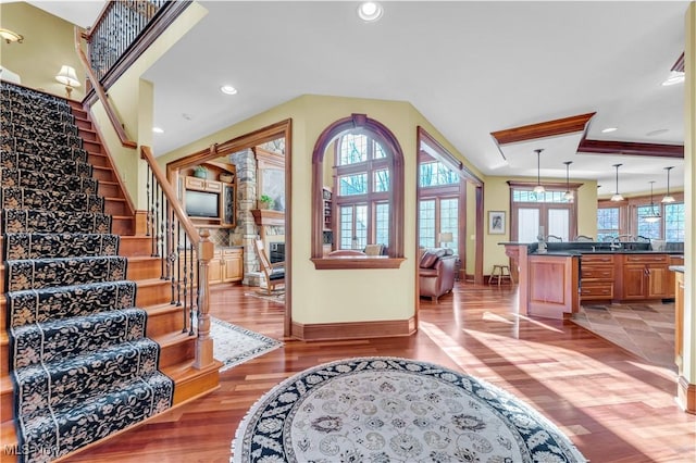 foyer entrance featuring baseboards, wood finished floors, stairway, recessed lighting, and decorative columns