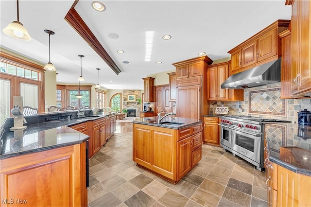 kitchen with under cabinet range hood, appliances with stainless steel finishes, a sink, a large island with sink, and recessed lighting
