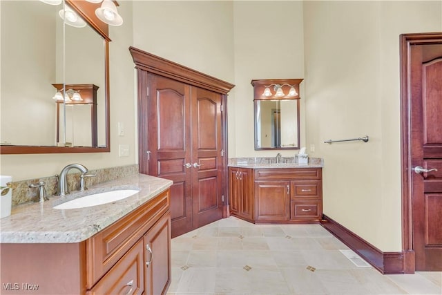 bathroom with two vanities, baseboards, and a towering ceiling