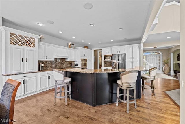 915 Creek View Dr, Aurora, OH 44202 - kitchen with appliances with stainless steel finishes, white cabinetry, light wood-style flooring, a breakfast bar area, and recessed lighting
