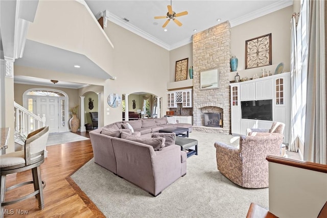 915 Creek View Dr, Aurora, OH 44202 - living room with arched walkways, healthy amount of natural light, a ceiling fan, ornamental molding, and a large fireplace