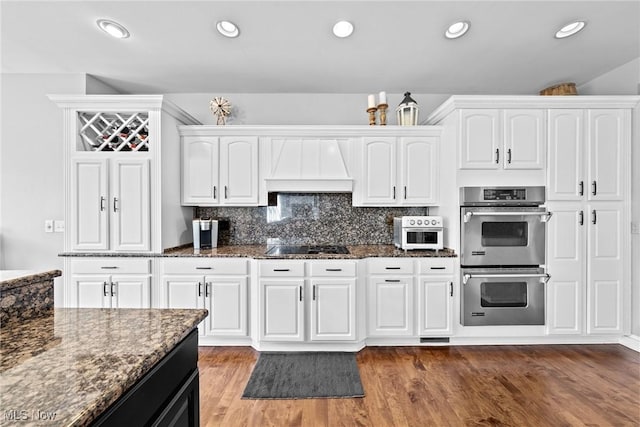 915 Creek View Dr, Aurora, OH 44202 - kitchen with double oven, dark stone counters, custom range hood, white cabinetry, and wood finished floors