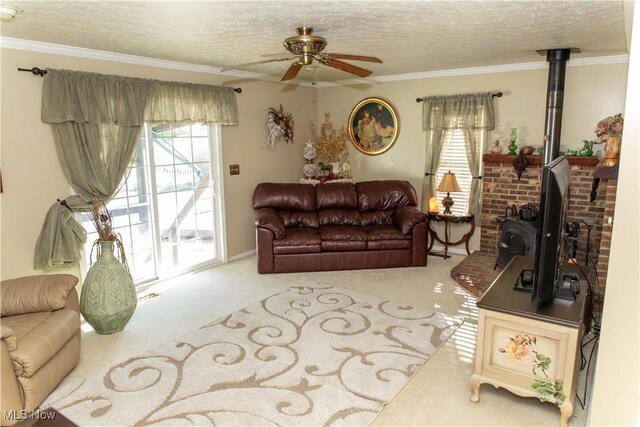 living area featuring a ceiling fan, carpet floors, a textured ceiling, ornamental molding, and a wood stove