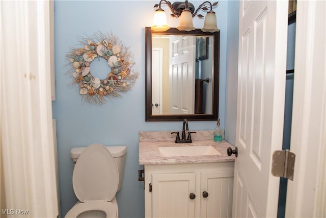 bathroom with vanity, toilet, and a chandelier