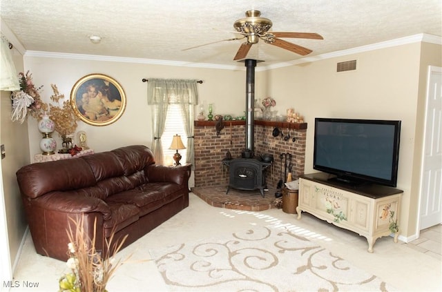 living area featuring a wood stove, ceiling fan, a textured ceiling, ornamental molding, and baseboards