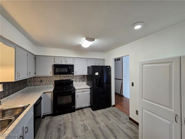 1308 17th St, Vienna, WV 26105 - kitchen with black appliances, decorative backsplash, a sink, light wood-type flooring, and light countertops