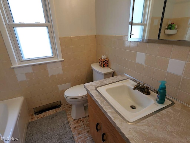 full bathroom featuring toilet, tile walls, vanity, a tub, and wainscoting