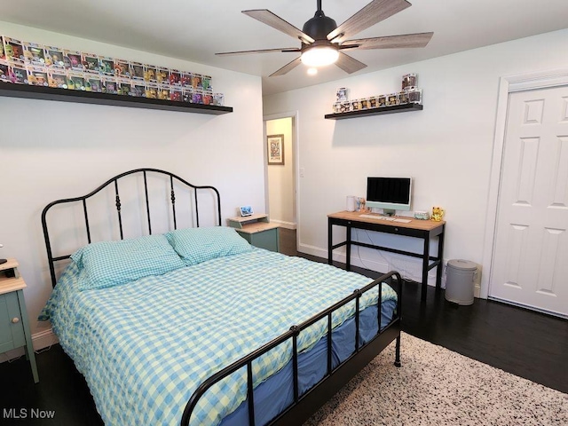 bedroom featuring baseboards, wood finished floors, and a ceiling fan