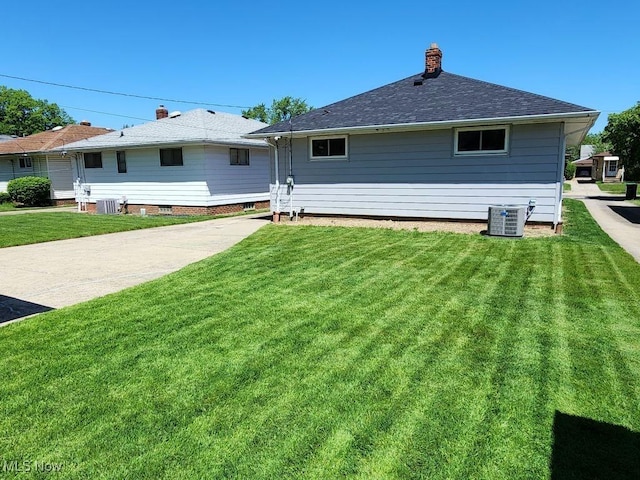 back of house with a lawn, central AC, and a chimney