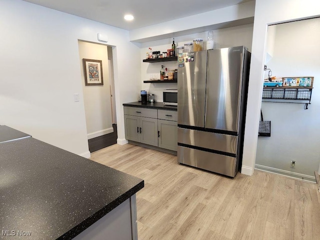 kitchen featuring stainless steel appliances, light wood-style flooring, baseboards, dark countertops, and open shelves