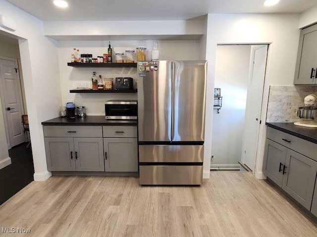 kitchen featuring appliances with stainless steel finishes, gray cabinetry, light wood-style flooring, dark countertops, and recessed lighting
