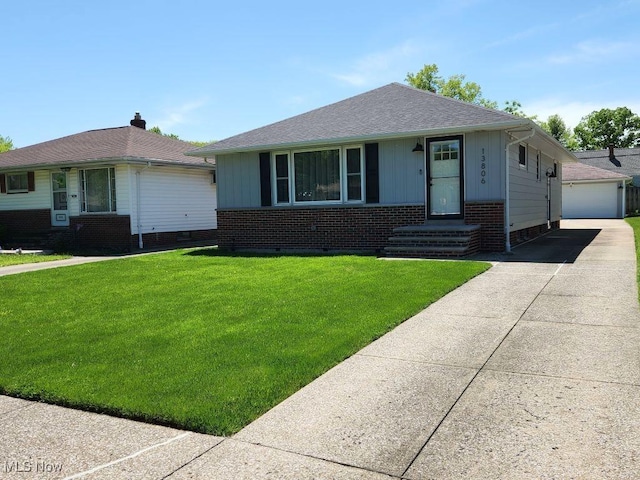 view of front of home featuring a front lawn, brick siding, a detached garage, and an outdoor structure