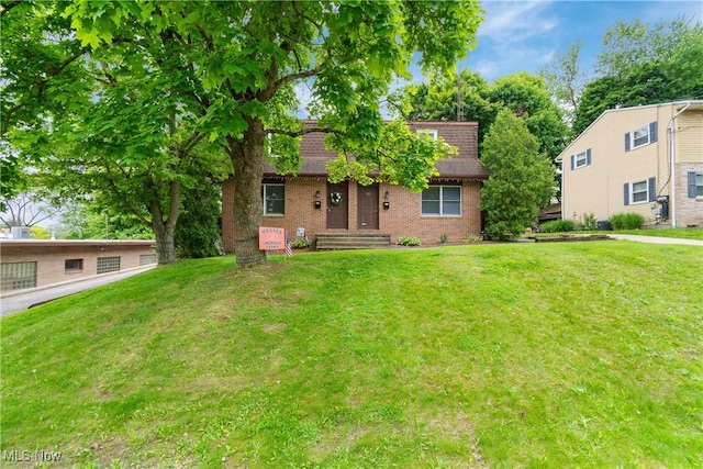 view of front of property with a front yard, brick siding, and roof with shingles
