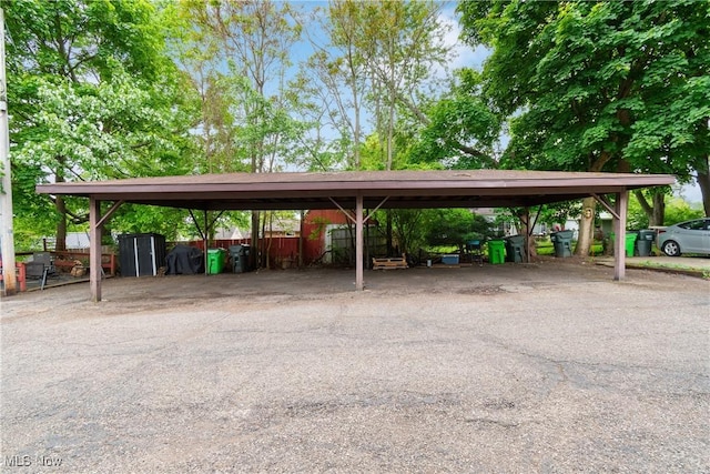 view of vehicle parking featuring a detached carport, fence, and driveway