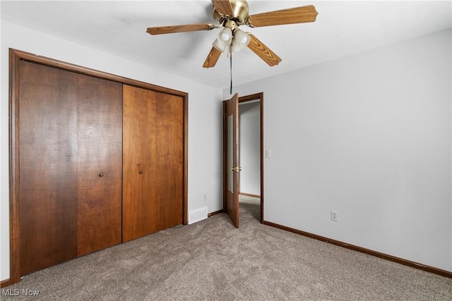 unfurnished bedroom featuring carpet flooring, a closet, baseboards, and a ceiling fan