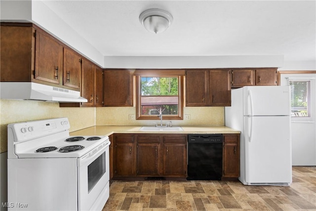 kitchen with white appliances, under cabinet range hood, a sink, light countertops, and plenty of natural light