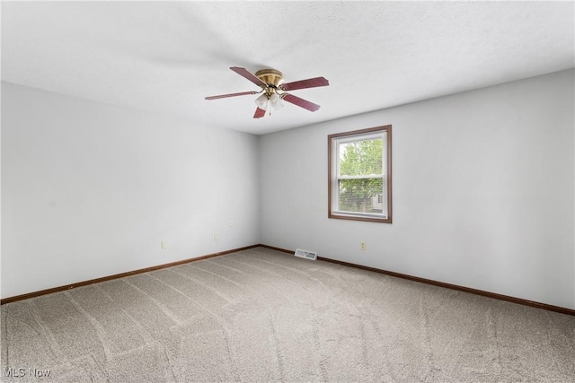 empty room with carpet floors, a ceiling fan, and baseboards