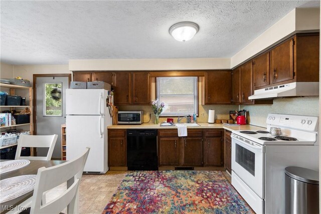 kitchen featuring white appliances, under cabinet range hood, a sink, light countertops, and a textured ceiling