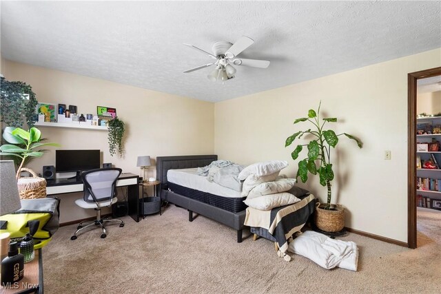 carpeted bedroom featuring a textured ceiling, baseboards, a desk, and ceiling fan