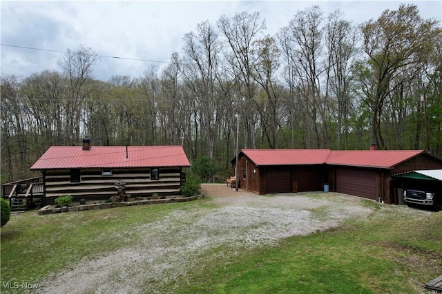 6141 Avon Rd NE, Carrollton, OH 44615 - view of side of property with metal roof, a garage, gravel driveway, a chimney, and a wooded view
