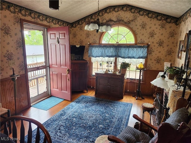 867 S 14th St, Sebring, OH 44672 - entrance foyer featuring wallpapered walls, wainscoting, light wood-style flooring, vaulted ceiling, and a textured ceiling
