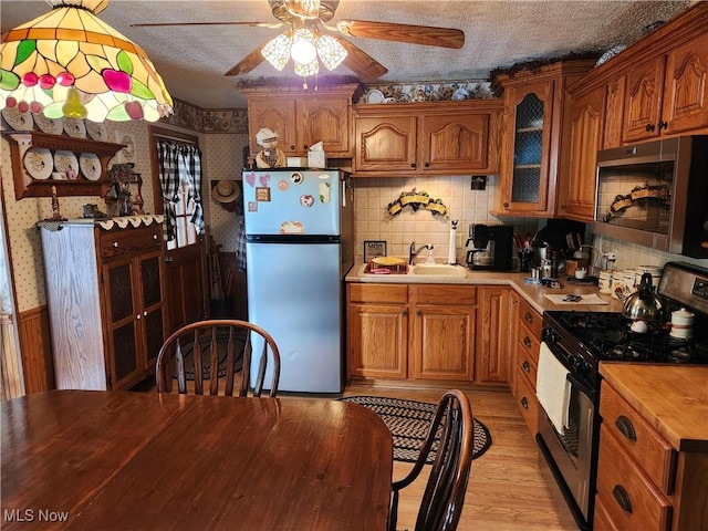 867 S 14th St, Sebring, OH 44672 - kitchen with appliances with stainless steel finishes, wallpapered walls, ceiling fan, wooden counters, and a sink