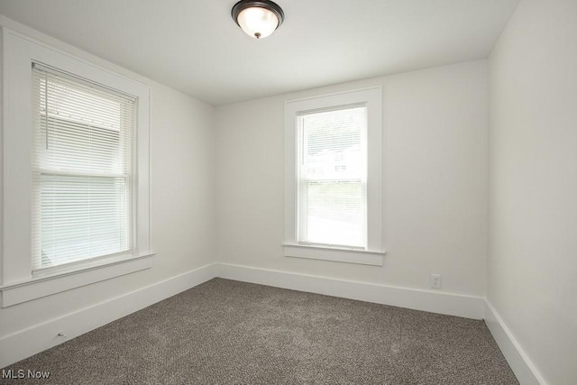 1197 E Ave, Akron, OH 44307 - empty room with dark colored carpet, baseboards, and healthy amount of natural light