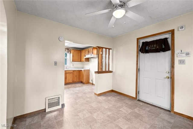 2021 17th St NE, Canton, OH 44705 - kitchen featuring baseboards, brown cabinets, under cabinet range hood, light countertops, and a ceiling fan