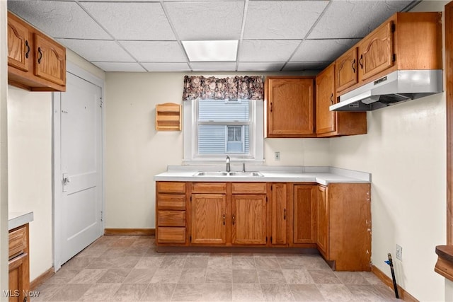 2021 17th St NE, Canton, OH 44705 - kitchen featuring a sink, under cabinet range hood, brown cabinets, light countertops, and a drop ceiling