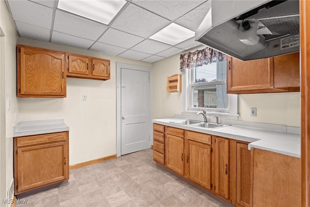 2021 17th St NE, Canton, OH 44705 - kitchen with a sink, under cabinet range hood, light countertops, baseboards, and brown cabinets