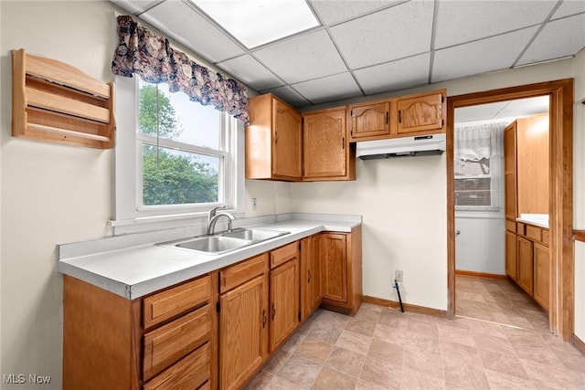 2021 17th St NE, Canton, OH 44705 - kitchen with a sink, brown cabinetry, light countertops, a drop ceiling, and under cabinet range hood