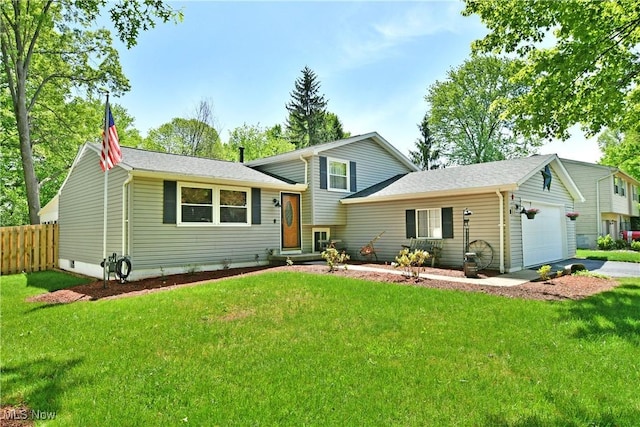 tri-level home with a garage, roof with shingles, and driveway