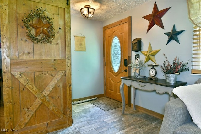 entryway with baseboards, wood finished floors, and a textured ceiling