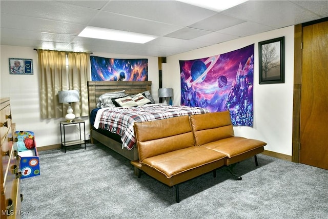 carpeted bedroom featuring baseboards and a drop ceiling