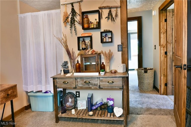 hall featuring carpet, a textured ceiling, and baseboards