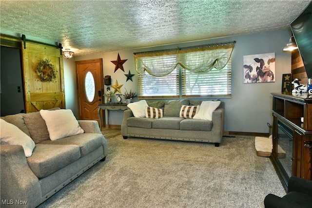 living room with a textured ceiling, carpet, a barn door, and baseboards