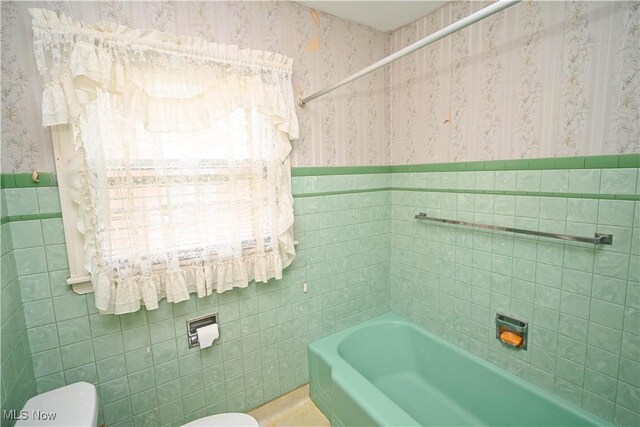 252 Rosemont Ave, Youngstown, OH 44515 - full bath featuring wallpapered walls, tile walls, toilet, a bathtub, and wainscoting