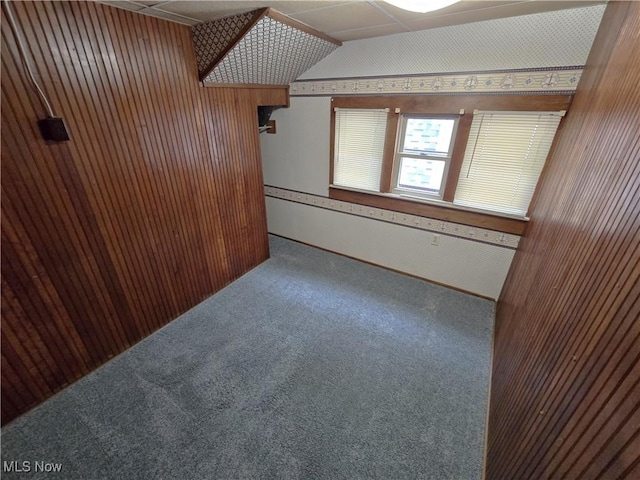 carpeted spare room with wooden walls