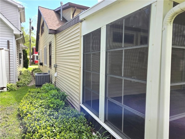 view of home's exterior with cooling unit and roof with shingles