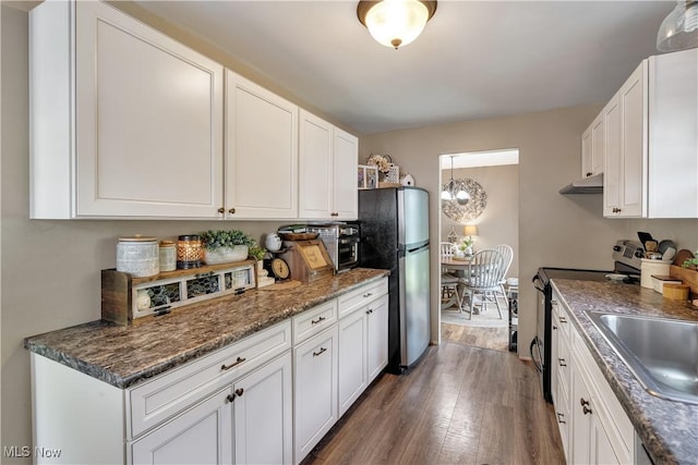 kitchen with stainless steel appliances, a sink, dark wood-style floors, white cabinetry, and under cabinet range hood