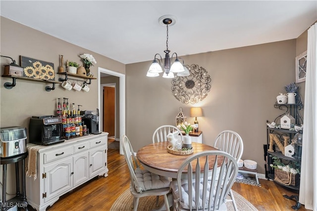 dining space featuring a chandelier, wood finished floors, and baseboards