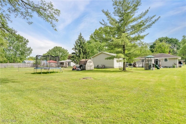 view of yard featuring a trampoline, a storage shed, a playground, and an outbuilding
