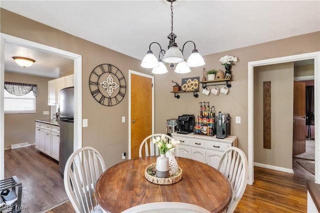 dining space with a chandelier, wood finished floors, and baseboards