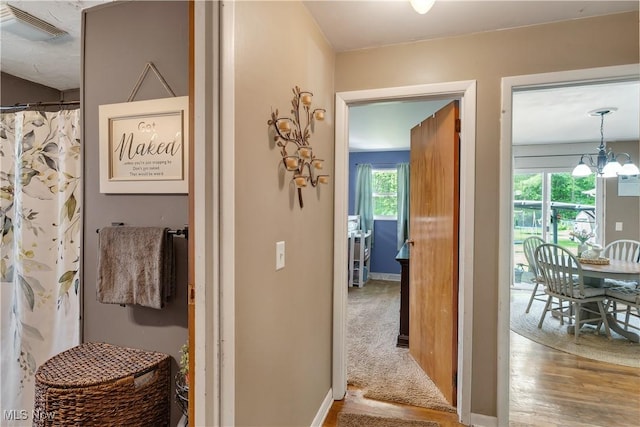 hallway with a chandelier and wood finished floors