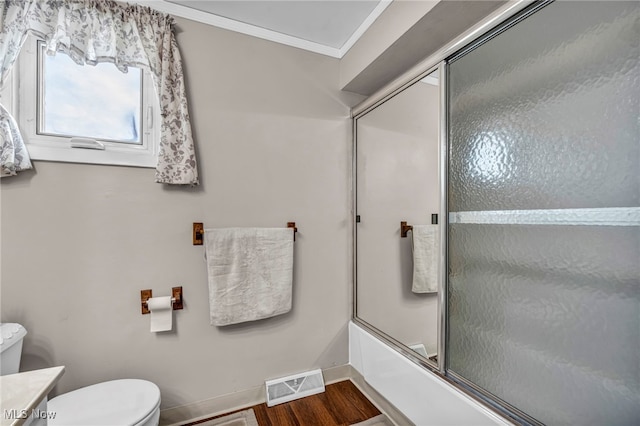 3226 Woodlawn Dr, Parma, OH 44134 - bathroom with toilet, crown molding, bath / shower combo with glass door, wood finished floors, and baseboards