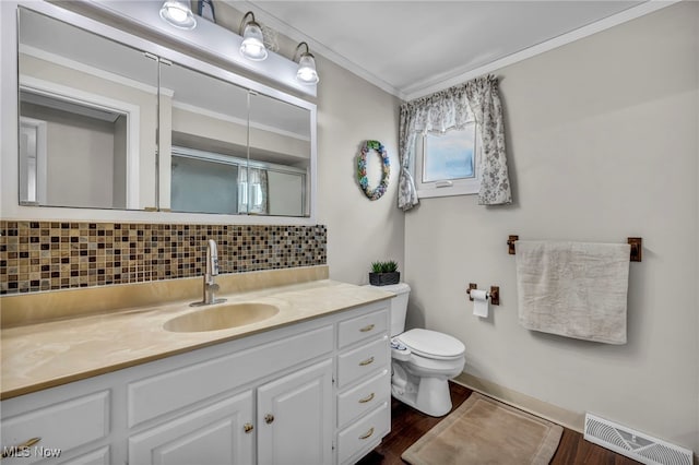 3226 Woodlawn Dr, Parma, OH 44134 - full bathroom with backsplash, toilet, wood finished floors, vanity, and crown molding