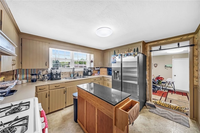 6395 Easton St NE, Louisville, OH 44641 - kitchen with a sink, white gas range oven, stainless steel fridge, a kitchen island, and a textured ceiling