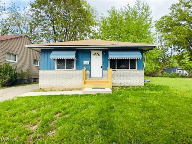 view of front of property featuring brick siding, a front yard, and board and batten siding